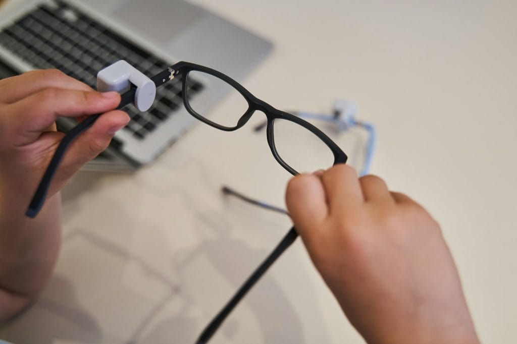Male child hands holding eyeglasses with black frame